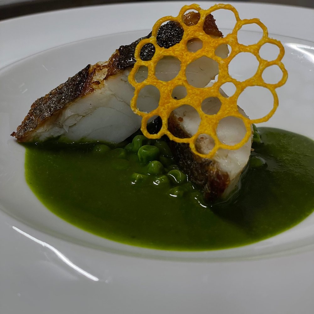 緑のソースを敷いた天然のハタのお魚料理
